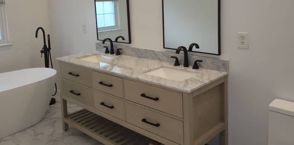 a newly renovated bathroom near Tysons Corner Virginia with a dual sink vanity countertop, two mirros, and a bathtub
